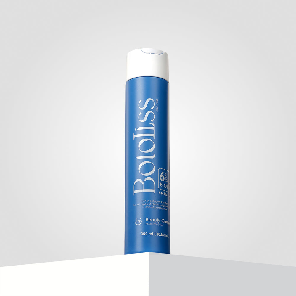 "Botoliss Biotin Shampoo" with a white cap is elegantly placed on a white surface, set against a light gray backdrop.