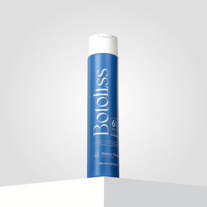 "Botoliss Biotin Shampoo" with a white cap is elegantly placed on a white surface, set against a light gray backdrop.