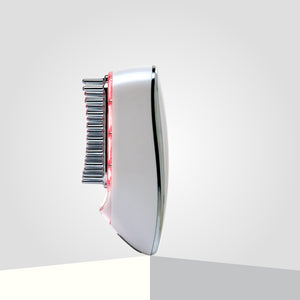 An electric laser hair growth comb with metallic bristles and red LED lights is showcased on a two-toned surface.