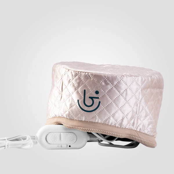 A quilted pink heating cap with an electric component and control switch, a logo on the side, is shown in a backshot.