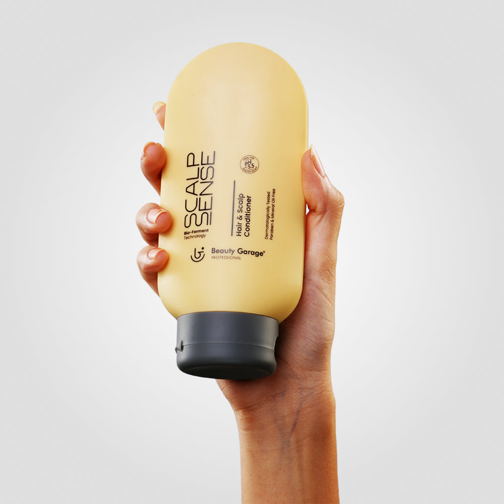 A yellow bottle of ScalpSense Hair & Scalp Conditioner by Beauty Garage sits elegantly on a white surface.