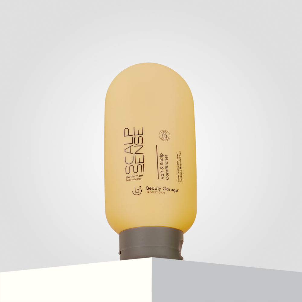 A yellow bottle of ScalpSense Hair & Scalp Conditioner by Beauty Garage sits elegantly on a white surface.