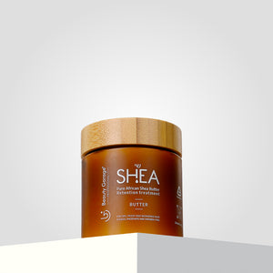 A brown jar with a wooden lid labeled "Shea Retention Hair Butter Mask" sits on a surface against a gray background.