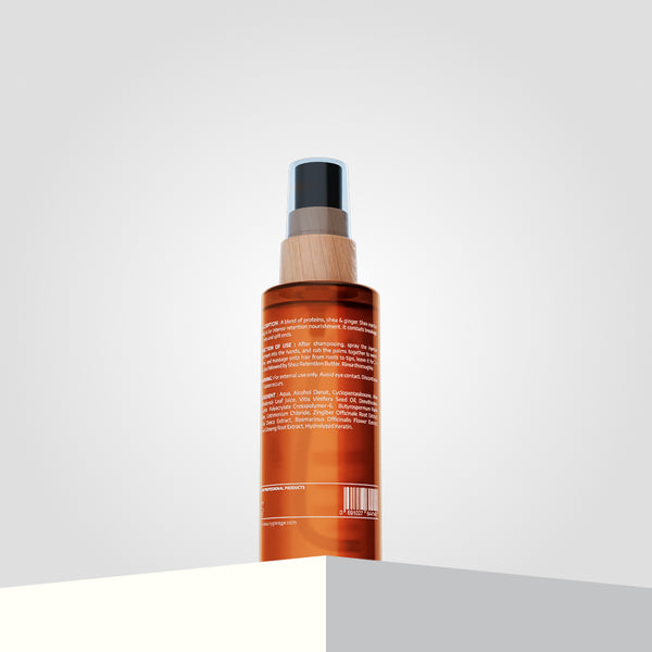 A brown spray bottle, labeled "Shea Retention Injector Spray" in white text, stands on a light-colored surface.