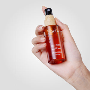 A hand holds a spray bottle labeled "Original Shea Retention Injector Spray" against a plain background.