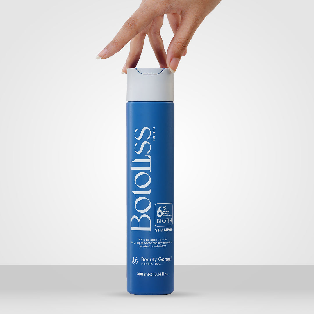 A hand reaches for a sleek blue cylindrical bottle labeled "Botoliss Biotin Shampoo."