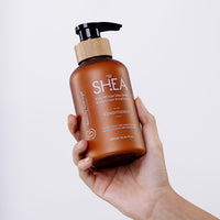 A hand holds a brown bottle of Shea Retention Conditioner, showcasing a pump top and bamboo accent.